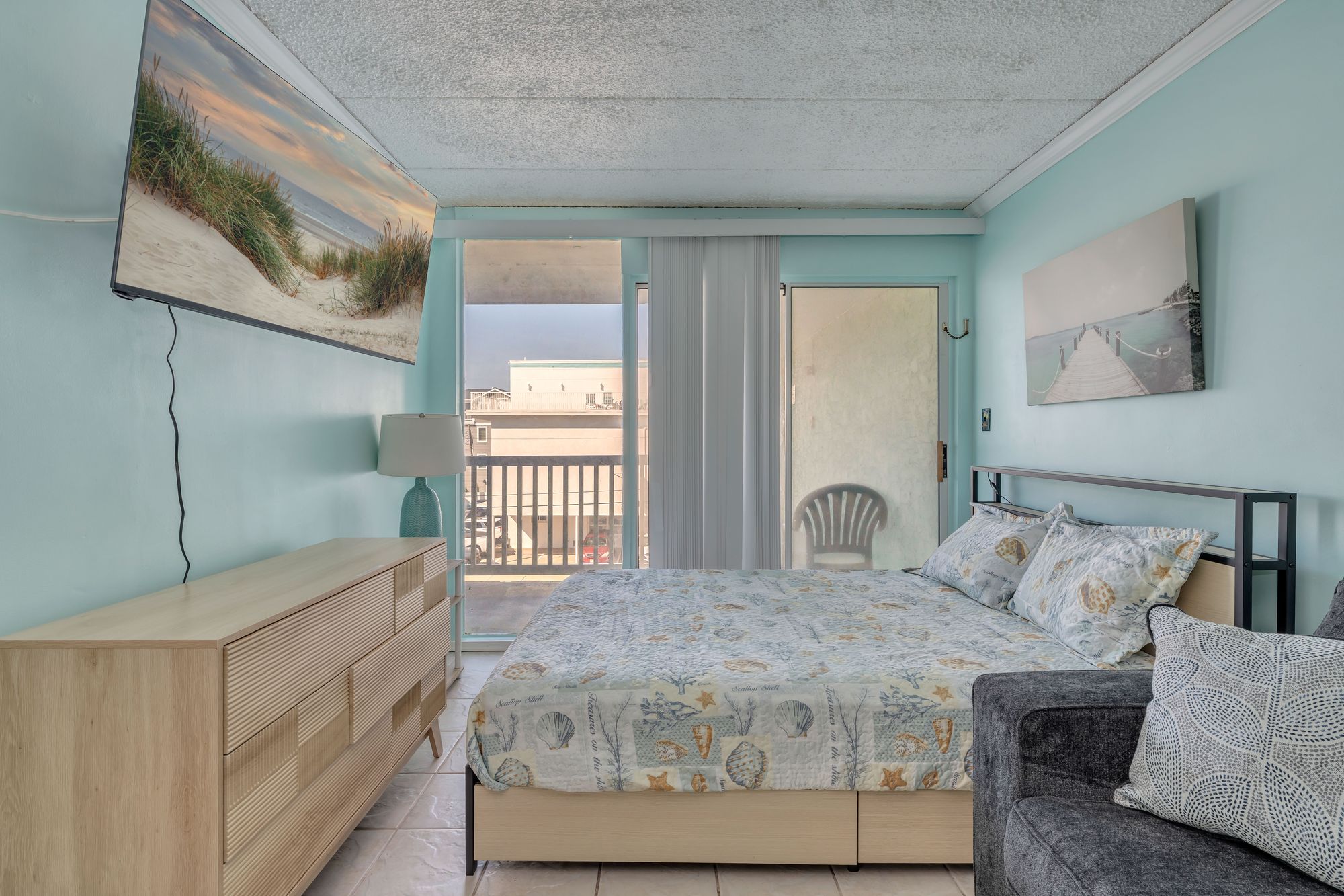 Bedroom with queen bed, dresser, and door to the balcony