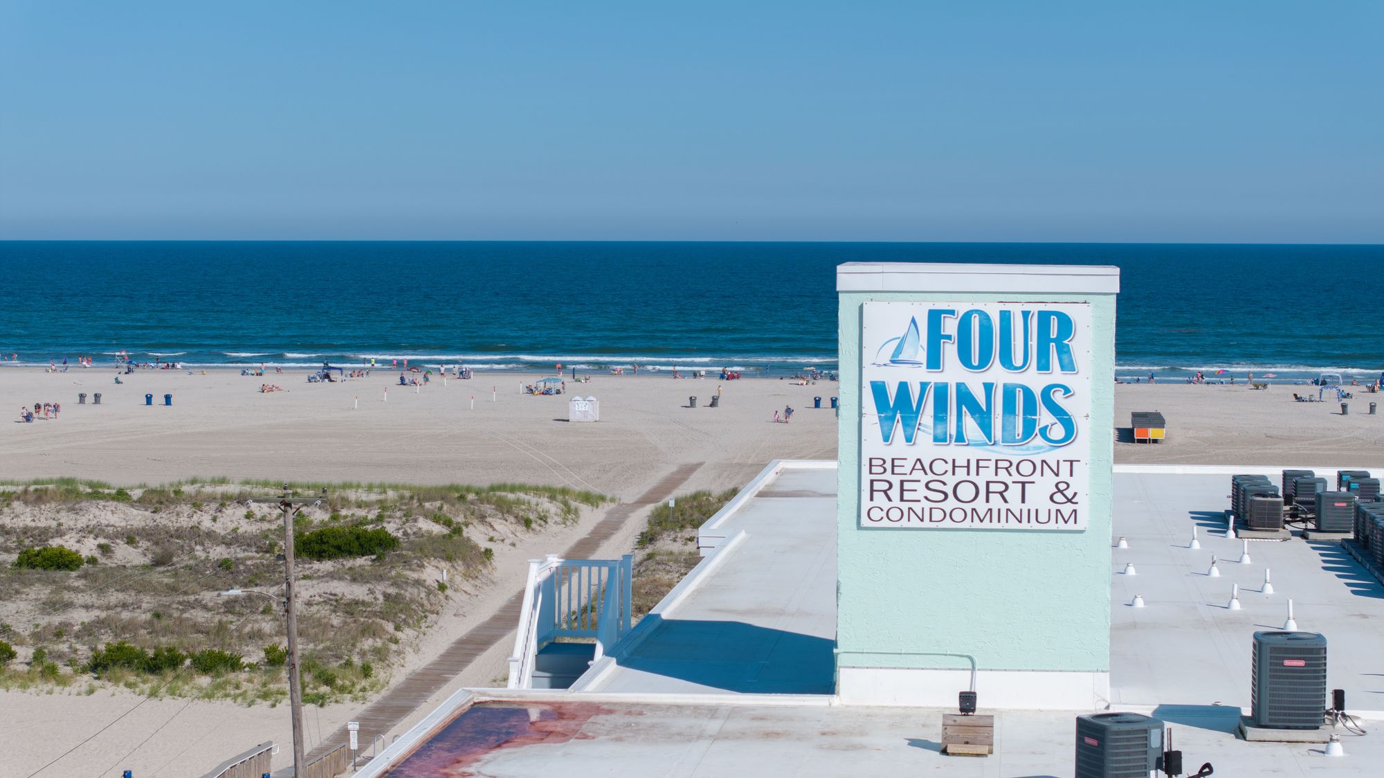 Four Winds sign with the beach and ocean beyond the building