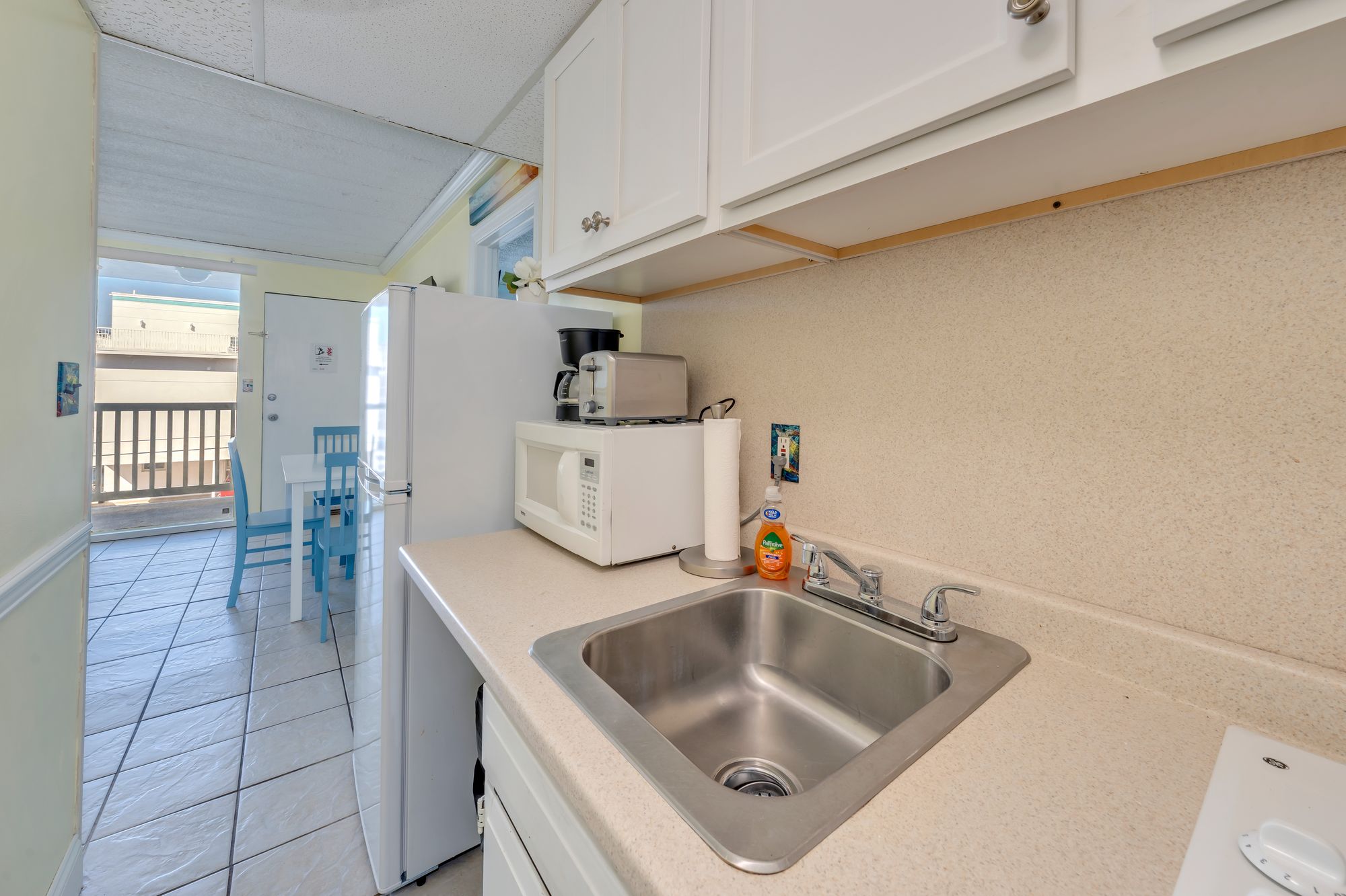 Kitchen sink and counter with the dining area and balcony door beyond
